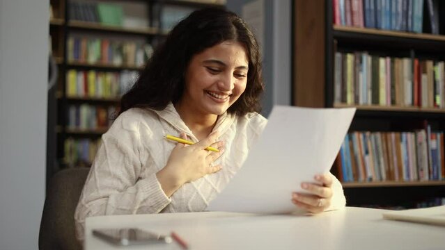 Portrait of happy student got an excellent grade mark for the test at university class Cute curly smiling girl looking at test in good mood indoors Exam passed Successful education concept