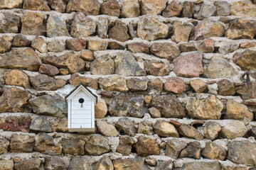 cabane à oiseaux accrochée sur un mur en pierres