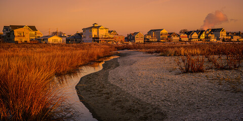 Beach houses and marshland at winter dawn on the coastal village in New England with curved sandy footpath at low tide - Powered by Adobe