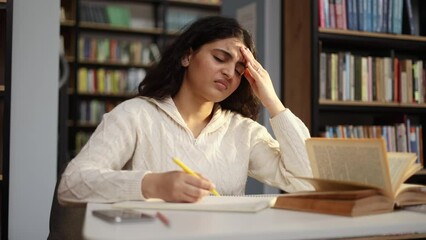 Unhappy young woman student with closing eyes suffering headache painful feelings chronic migraine high or low pressure vision problem after hard work with preparing for exam at university library