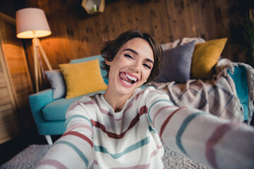 Obraz premium Portrait of overjoyed cheerful pretty lady take selfie tongue lick teeth have good mood pastime house inside