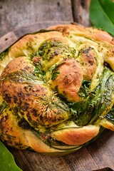 Bread with herbs. Bread braid with wild garlic, chives and pesto. Top view, wooden background.