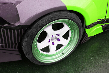 close-up of the rear lightweight alloy wheel of a sports car with a light green livery on the body