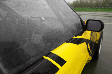 close-up of a polycarbonate side window of a sports car with a yellow livery on the body