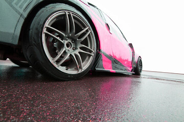 a sports car for drifting with a pink livery on the body stands in a parking lot on a white background