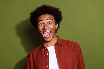 Fototapeta na wymiar Photo portrait of attractive young man tongue out have fun fooling dressed stylish brown clothes isolated on khaki color background