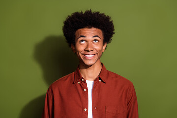 Fototapeta na wymiar Photo of funky cheerful man with afro hairstyle dressed brown shirt look up at offer empty space isolated on khaki color background