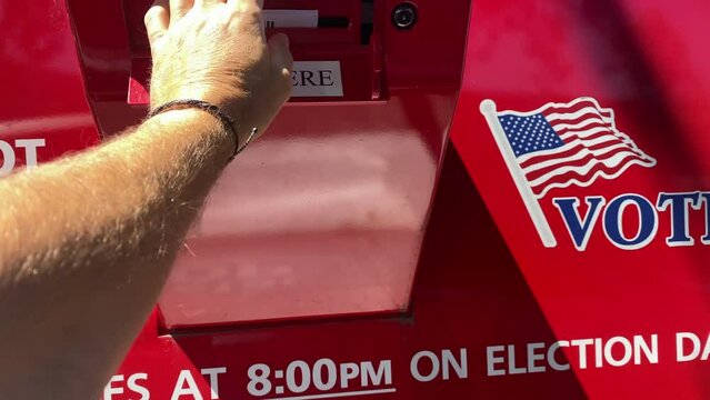 Point of view of person at a mail-in voting box dropping off sealed election ballot.