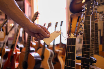close up detail of a hand holding a guitar purchase tag - obrazy, fototapety, plakaty