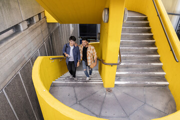 two friends walking up colorful stairs in London while laughing