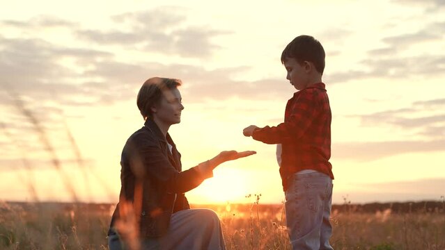Boy extends hand to mother signifying sense of trust. Boy through connection experiences care with mother. Boy in midst of nature with mother reaches out to sharing profound feeling of freedom