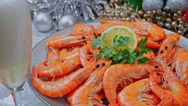 Boiled shrimps on a plate rotating, Christmas New Year decoration, pour champagne into a glass. Close up