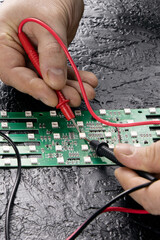 The master tests the LEDs on the microcircuit using a multi-meter. Checking LEDs. LEDs on a microcircuit. Vertical orientation.