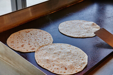 Traditional Flour Tortillas Cooking on Seasoned Griddle in Taqueria