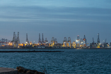Obraz premium Cranes with beautiful lighting in the port on the blue sea in the evening