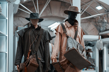 Two male mannequins in duster coats and cowboy hats in the window of a men's clothing boutique.