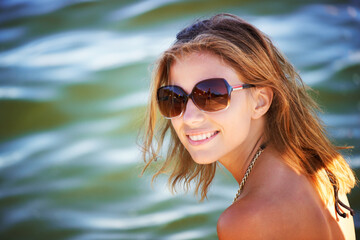 Lake, portrait or happy woman in nature to relax with sunglasses, freedom or adventure in summer. Smile, paradise or female person in river water or dam for holiday travel, peace or outdoor vacation
