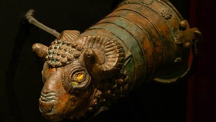 Antique bronze embroidered ram head on a dark background. Selective focus.