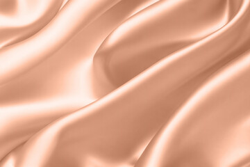 Abstract background, folds of silk fabric in peach fuzz color.