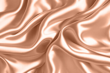 Abstract background, folds of silk fabric in peach fuzz color.