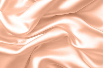 Abstract background, folds of silk fabric in peach fuzz color.