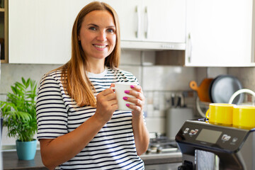 Woman enjoying freshly prepared coffee near modern coffee machine in kitchen
