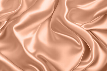 Fototapeta premium Abstract background, folds of silk fabric in peach fuzz color.