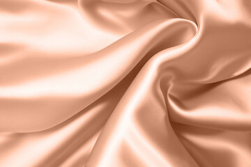 Obraz premium Abstract background, folds of silk fabric in peach fuzz color.
