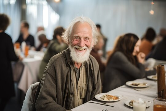 Happy homeless old man sitting at a table at a charity dinner.