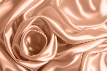Abstract background, folds of silk fabric in peach fuzz color.