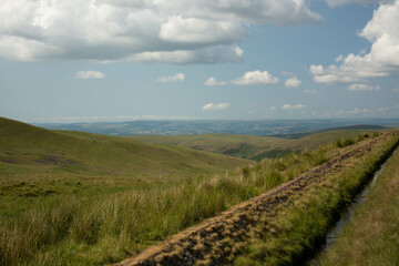 Beautiful shot of a dirt trail along rural green hills in Wales