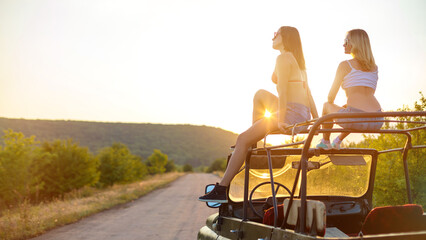 Couple of girls travelling on the vintage cabriolet. Rural background. - obrazy, fototapety, plakaty