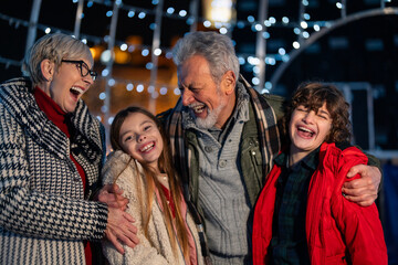 Portrait of cheerful grandparents with grandchildren at Christmas market.