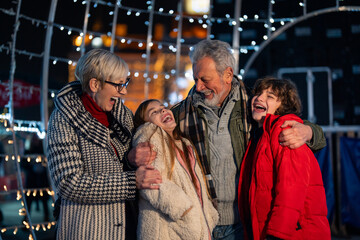 Happy grandparents and grandchildren enjoying the Christmas fair during winter holidays.