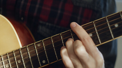 Close-up of bearded young adult man playing acoustic guitar. Camera moving up