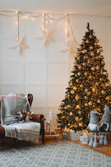 Artificial Christmas tree with golden Christmas tree toys, retro sofa and holiday lights near white wall, garland with big white stars