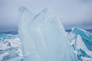 Crystal clear transparent ice pieces on frozen Baikal lake in winter day. 