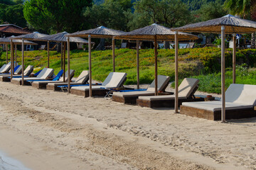 Fototapeta na wymiar Clean beach with beds under straw umbrellas