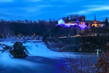 Laufen, Switzerland - January 08. 2022: Rhinefalls and Castle Laufen with Christmas illumination at the blue hour time