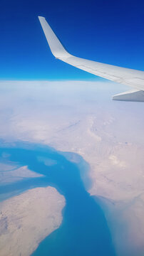 View from the window of plane on blue sky and earth with landscape of desert, sea and canals in Emirates. High quality photo