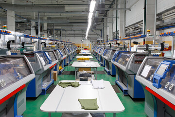 A row of industrial textil flat knitting machines in a knitwear factory.