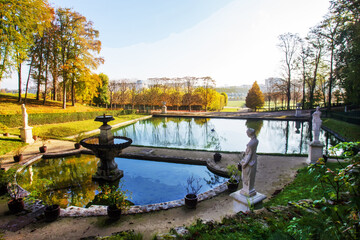 Fototapeta na wymiar Idyllic landscape with pond statues, potted plants in Saint-Cloud park - sunny, orange day in autumn i