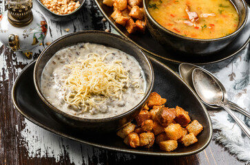 Mushroom cream soup with cheese, croutons in bowl on rustic wooden background. Healthy food, top view