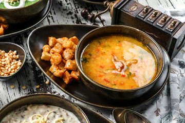 Vegetables soup with bacon, spices and croutons in bowl on rustic wooden background. Healthy food, top view