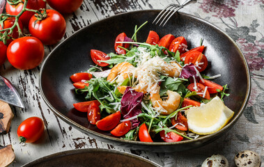 Healthy shrimp salad with arugula, tomatoes, lettuce in plate on rustic wooden background. Healthy food, top view