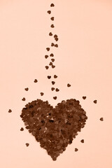 Heart made of shiny red small decorative hearts on a pink background. Peach fuzz is color of year 2024.