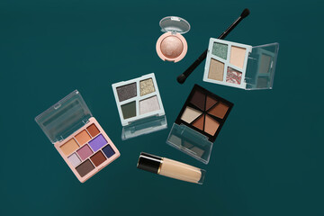 Beautiful palettes of eyeshadows and concealer on green background