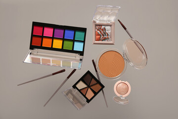 Beautiful palettes of eyeshadows and different decorative cosmetics on grey background