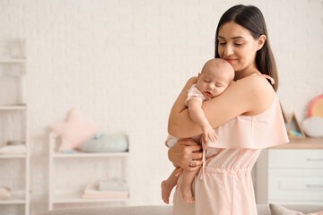 Happy mother with cute little baby in children's room