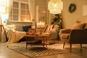 Interior of living room decorated for Hannukah with armchairs and table at night